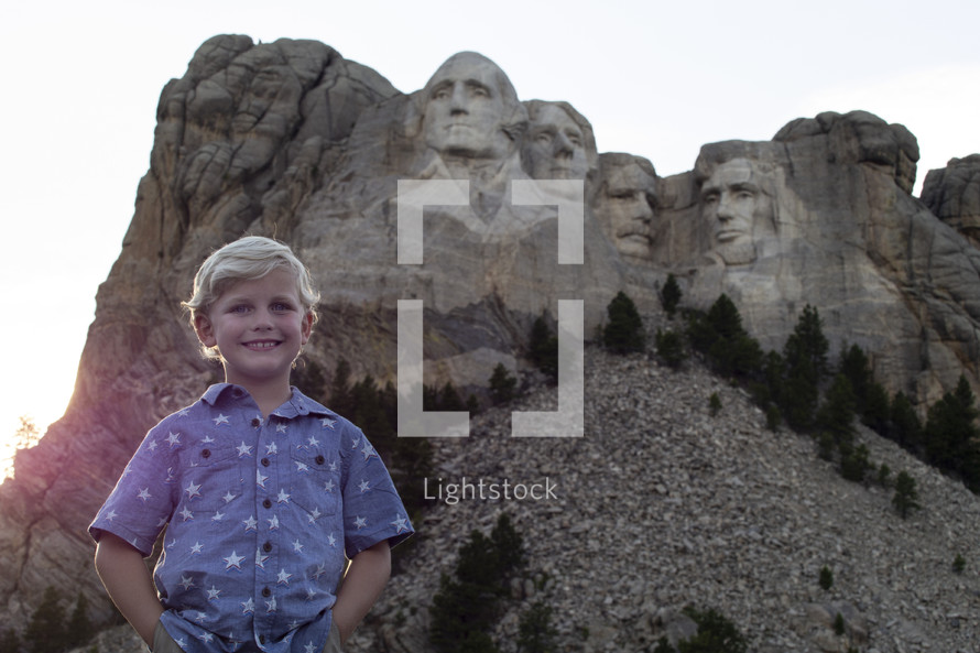 boy child smiling in front of Mount Rushmore 