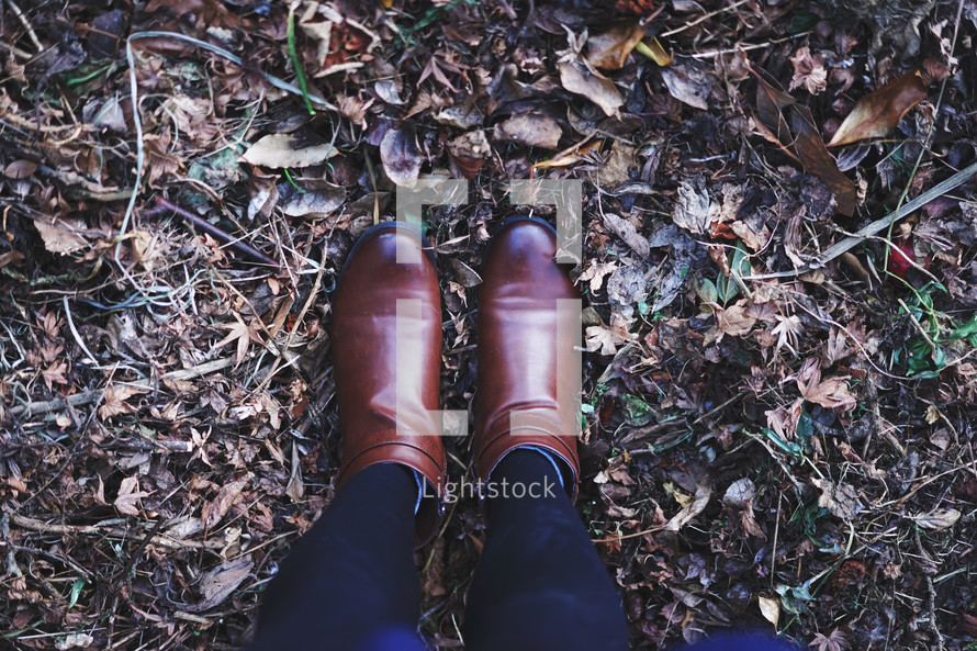 woman in boots standing in fall leaves 