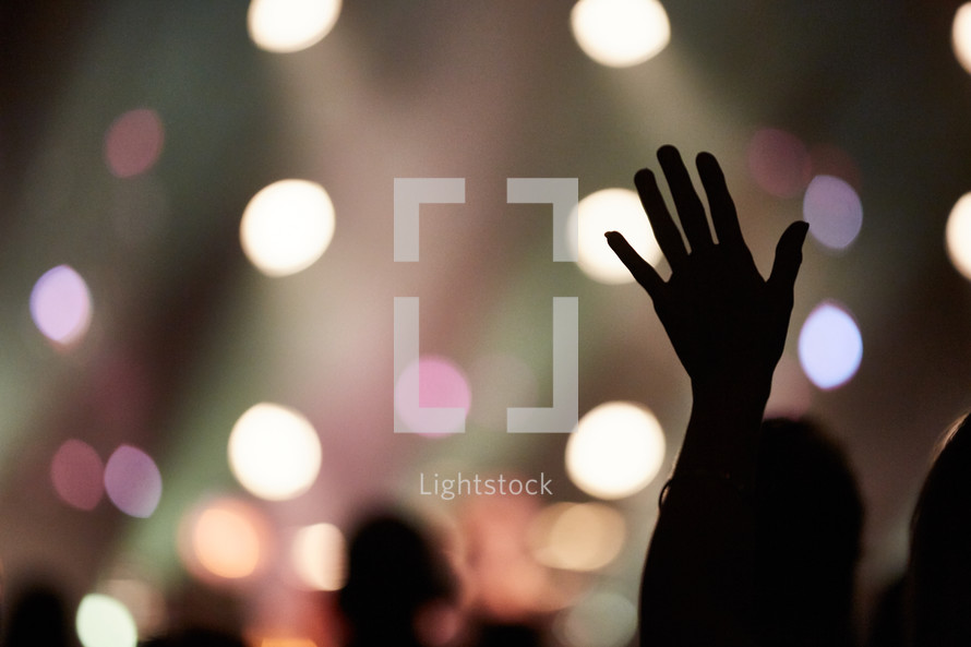 silhouette of a raised hand and bokeh background 