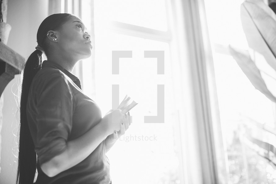 woman looking up to God standing in a window 