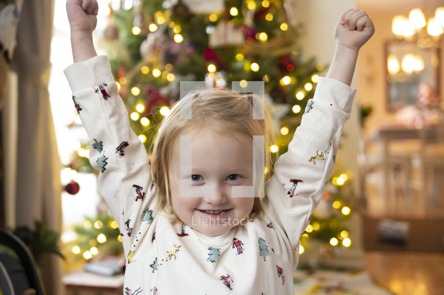 Little girl playing in front of a Christmas tree
