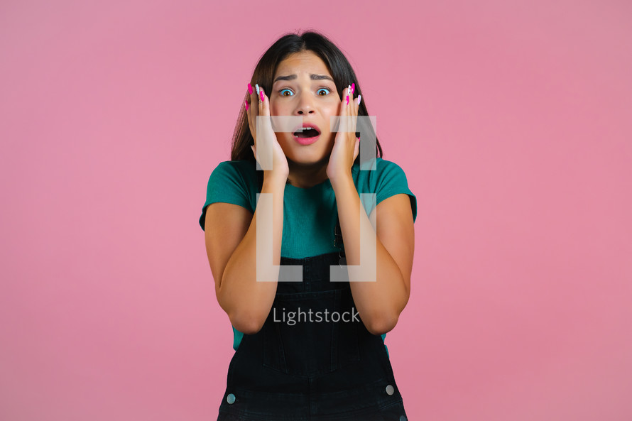 Frightened woman shocked isolated over pink background. Stressed pretty girl because of bad news