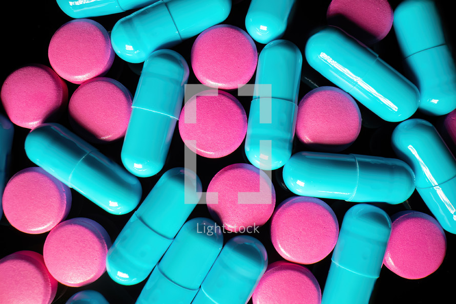 Macro view of colorful capsule pills. Pharmaceutical medicament for health. Dietary supplements, useful vitamins concept. Neon light, black background. High quality 