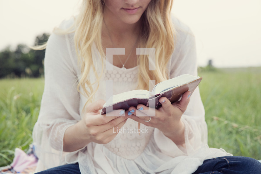 woman sitting outdoors reading a book 