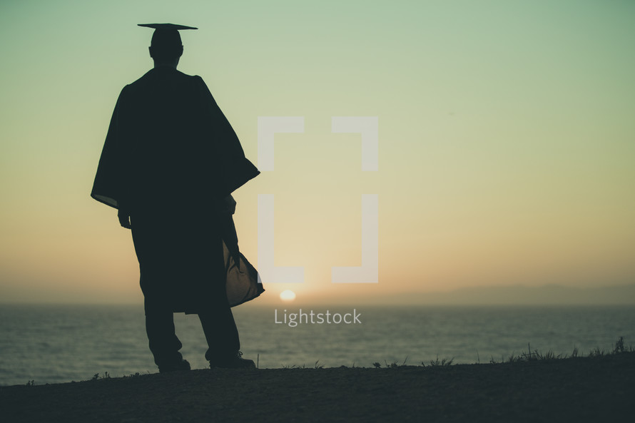 silhouette of a graduate on a beach at sunset 