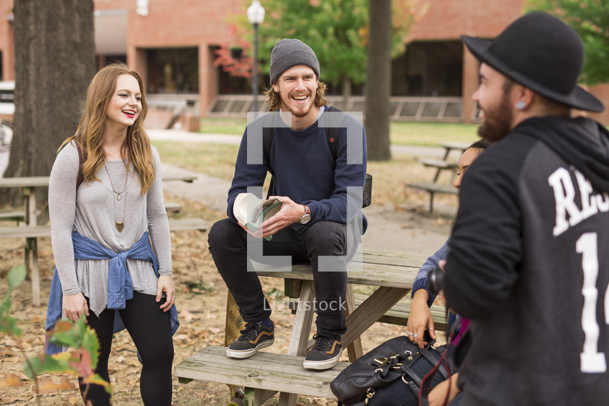 students gathered sitting around picnic table on campus 