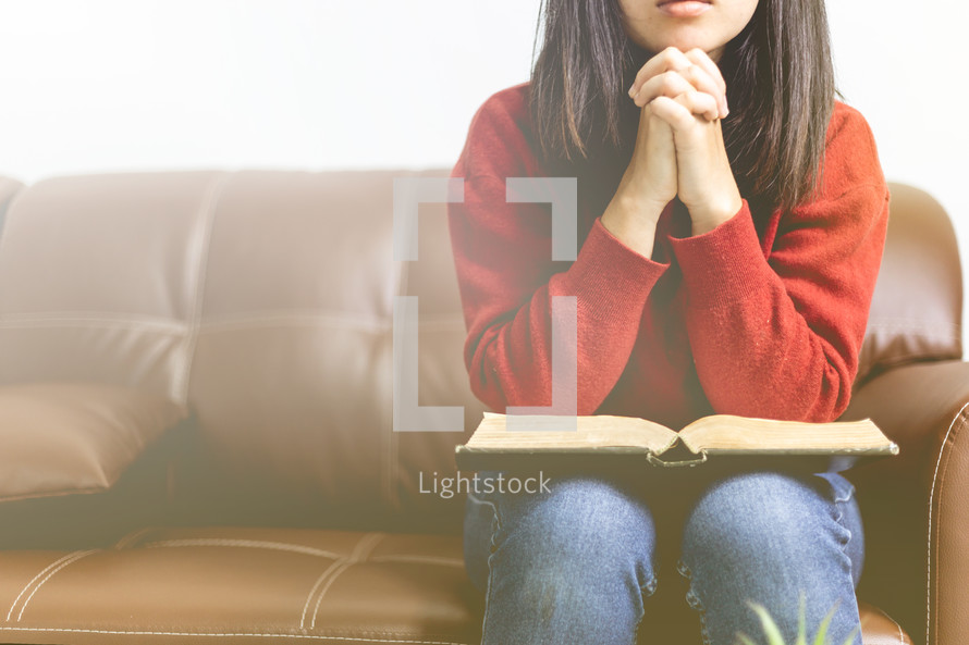 a woman praying with a Bible on her lap 