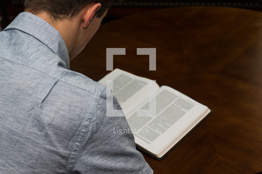 a man reading a Bible on a coffee table 