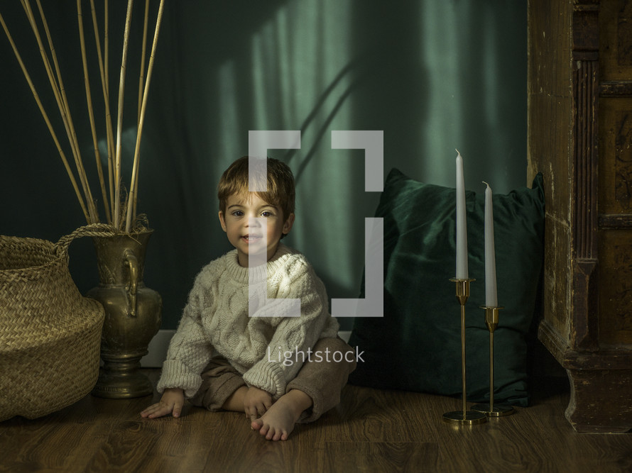 toddler boy sitting on a playroom floor 