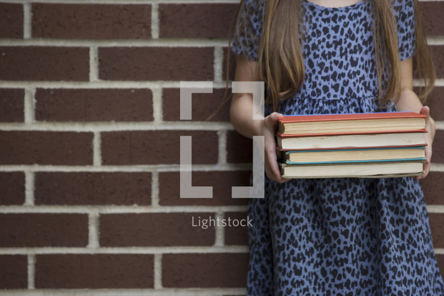 a girl holding a stack of books 