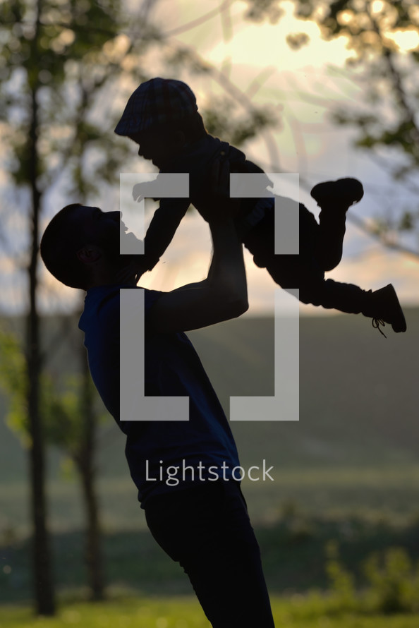silhouette of a father picking up his son 