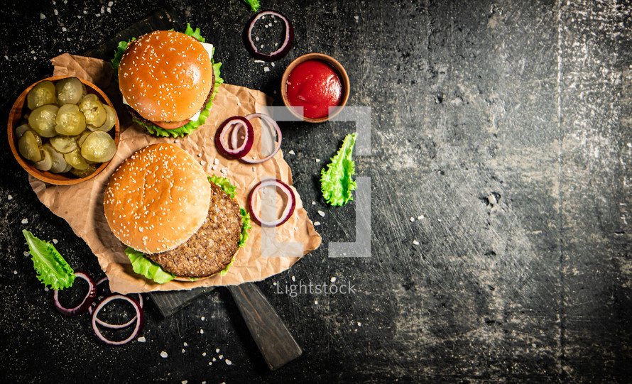 A burger on a stone board on a table. On a black background. High quality photo