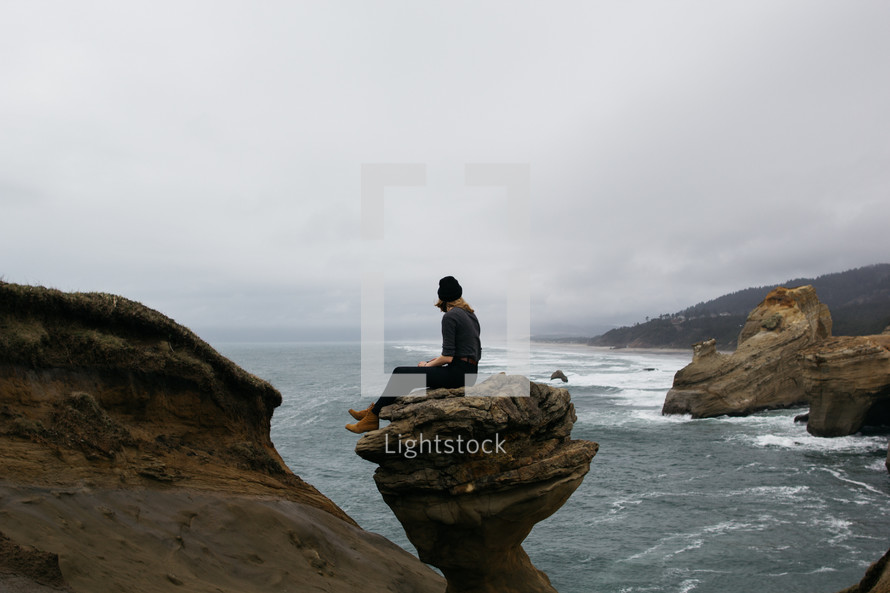 a woman sitting on a rock peak 