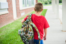 a boy carrying a book bag to school 
