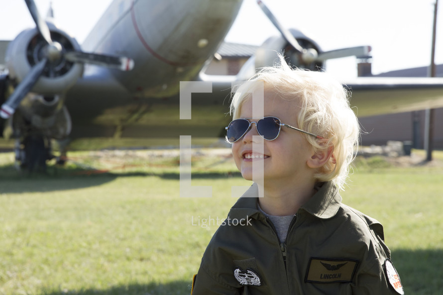 boy child in aviator shades in front of a bomber 
