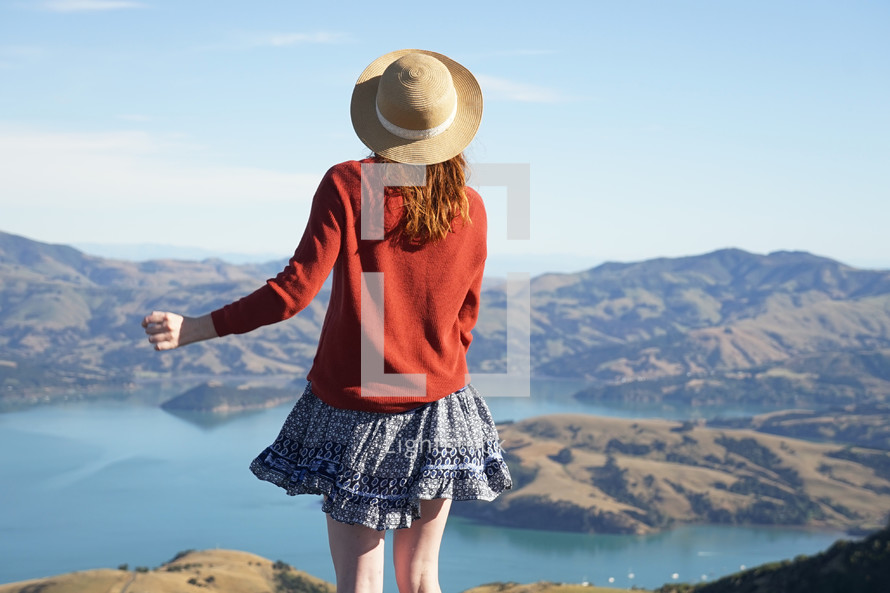 a woman standing on a mountaintop looking down at the water below 
