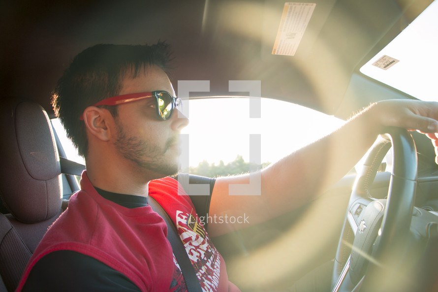 face of a man in sunglasses driving a car 