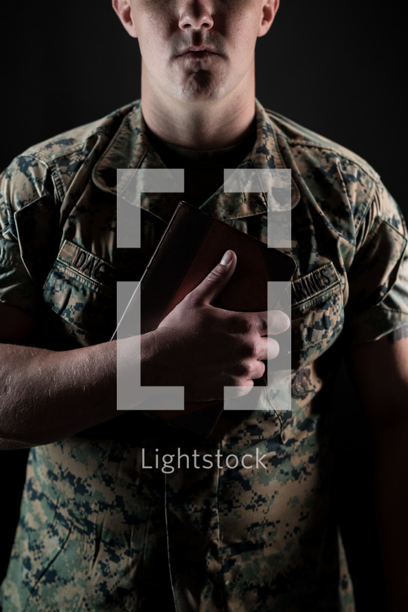 a serviceman holding a Bible against his chest 