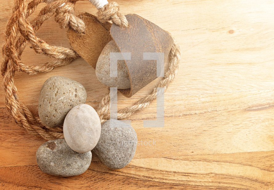 A Sling Shot and Stones on a Wooden Table from the Story of David and Goliath in the BIble 