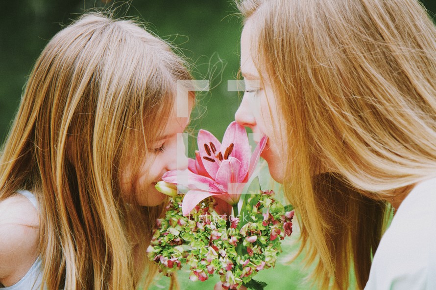 Mother and daughter smelling a bouquet of flowers.