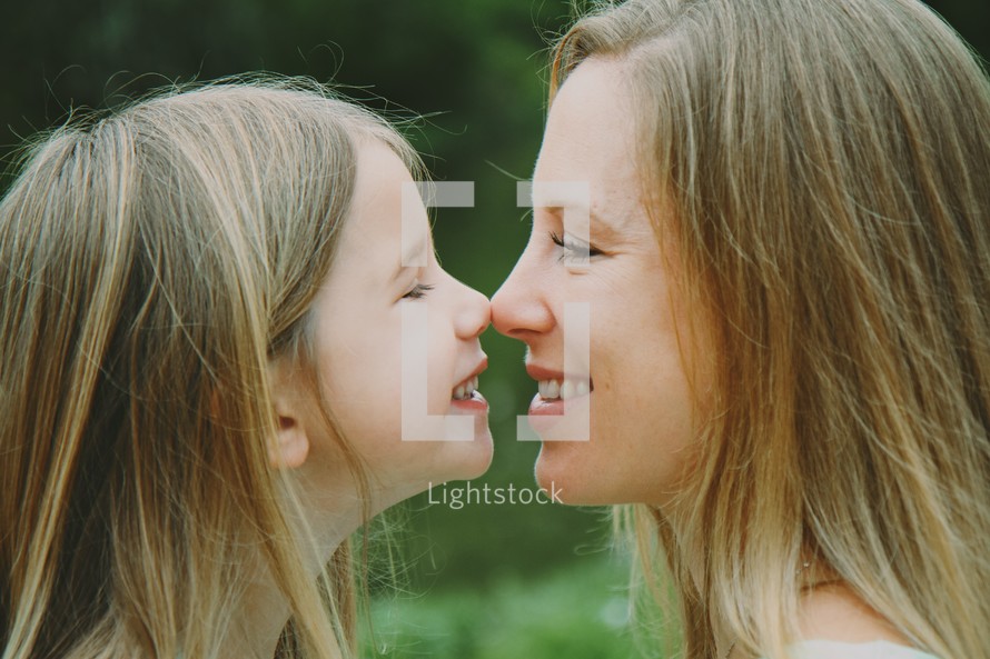 Smiling mother and daughter touching noses.