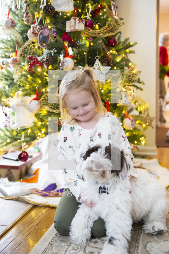 Little girl in front of Christmas tree with dog
