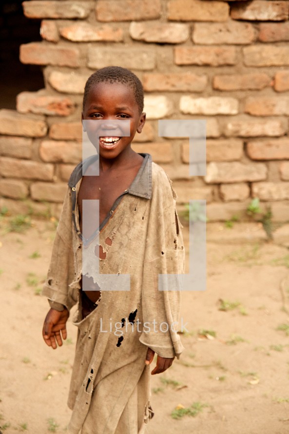 smiling face of a boy child in tattered clothing 