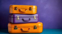 Orange and purple suitcases on a purple wall. Travel concept. 
