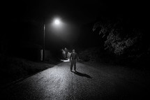 a man standing in the middle of a street at night looking up to God 