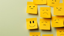 One happy face with sad faces drawn on yellow sticky notes. 
