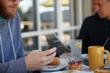 a man checking his cellphone over breakfast 