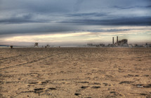 beach view of a factory with smoke stacks