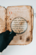 Historian scientist in gloves reading antique book with magnifying glass. Translation of religious literature. Manuscript with ancient writings. Treasures of the past. Museum piece.