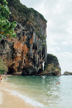 people swimming in the ocean and sea cliffs 