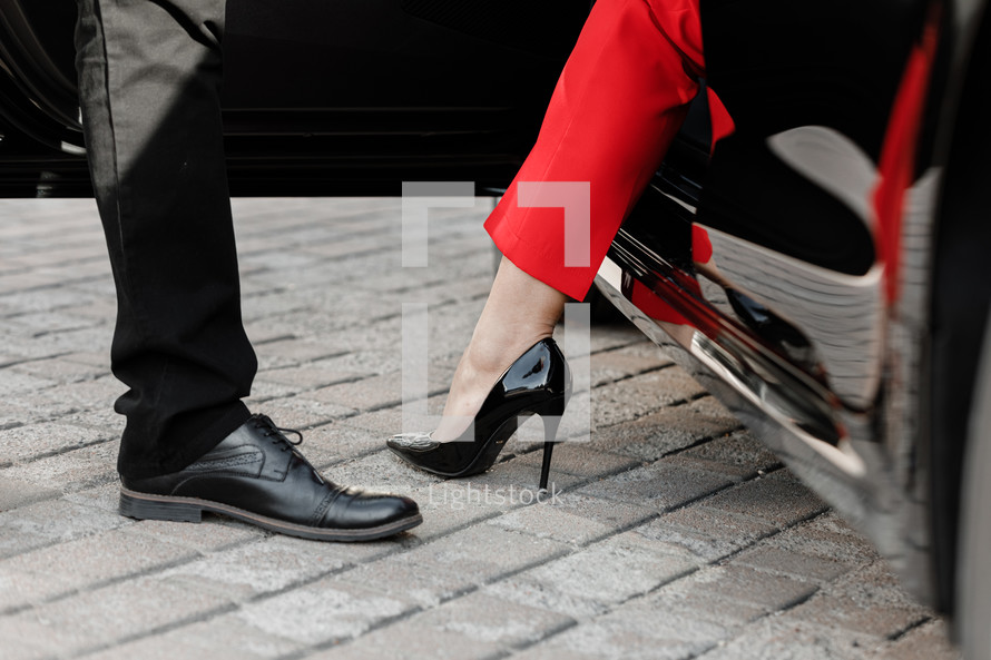 Close up image of a business woman getting out of her car with high heels shoes