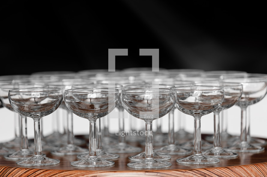 Many elegant empty glasses of wine or champagne on the wooden table in wedding day. Set of blank empty glasses displayed in rows. Preparation for the holiday.