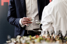 Handsome and successful businessman in stylish suit holding glass of martini on party, corporate party, conference, forums, banquets, closeup. selective focus.