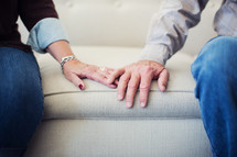 elderly couple touching hands 