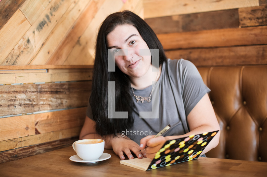 a young woman journaling sitting in a table at a cafe