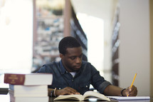 a college student taking notes at a table in a library.