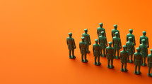 Plastic green army men in formation on an orange background.