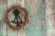 crown of thorns around skeleton keys on an old green wood background 