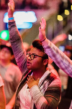 Woman in a church service with arms raised in worship.