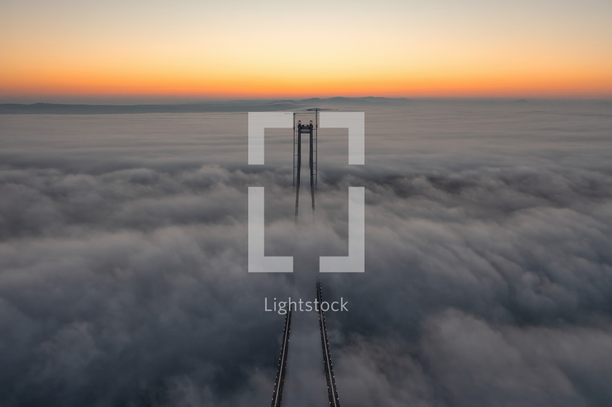 Aerial footage of bridge peeking out from clouds at sunset