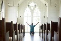 a man kneeling with hands raised in worship at church 