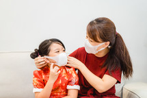 a mother helping a child put on a face mask 