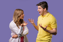 Young couple emotionally quarreling on violet background. Concept of conflict, problems in relationships. White american woman and man. High quality 