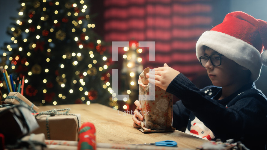 Children preparing Christmas gifts for his family on table