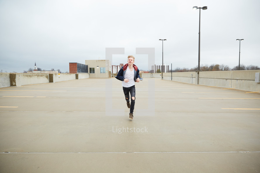 teen boy running in a parking deck 