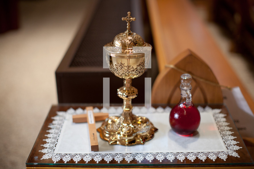 chalice, cross and holy water on table